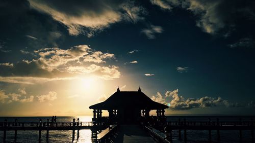 Silhouette pier over sea against sky during sunset