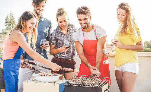 Happy friends preparing food on barbecue