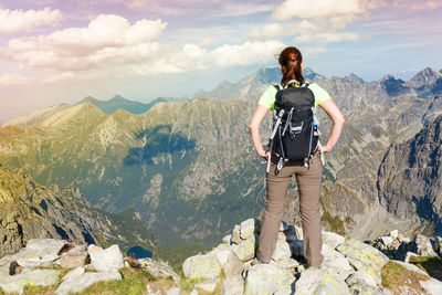 Rear view of woman standing on landscape against cloudy sky