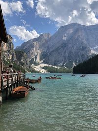 Sailboats moored on sea by mountains against sky