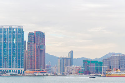 Sea by modern buildings against sky in city