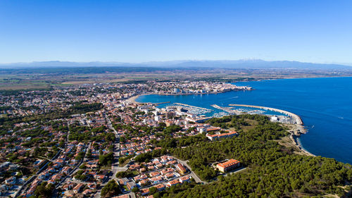 High angle view of town by sea against clear sky
