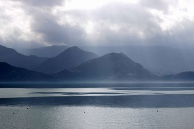 Scenic view of sea and mountains against sky