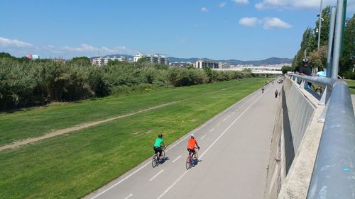 People riding bicycle on road against sky