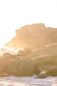 Rock formations by sea against clear sky