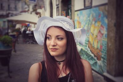 Thoughtful young woman wearing hat on footpath