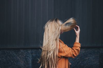 Woman with long hair standing against wall