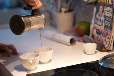 Close-up of hand pouring coffee in cup