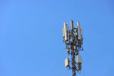 Low angle view of communications tower against clear blue sky