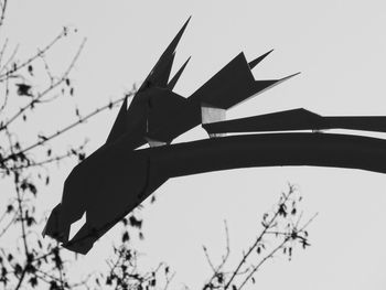 Low angle view of silhouette bird flying against clear sky