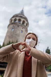 Low angle view of man holding glass against sky