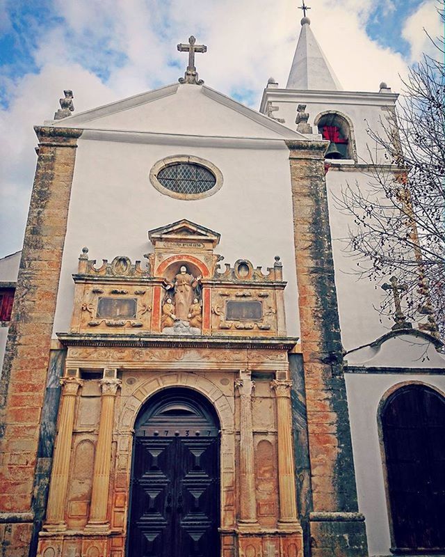 building exterior, architecture, religion, church, low angle view, built structure, place of worship, spirituality, cross, sky, cathedral, facade, arch, window, day, outdoors, entrance, clock tower