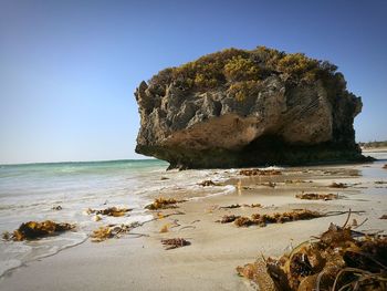 Rock formation on beach against clear sky