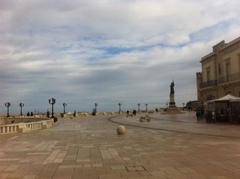 Street amidst buildings against cloudy sky