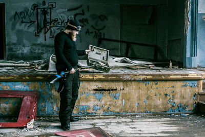 Full length of man standing with gun in abandoned room