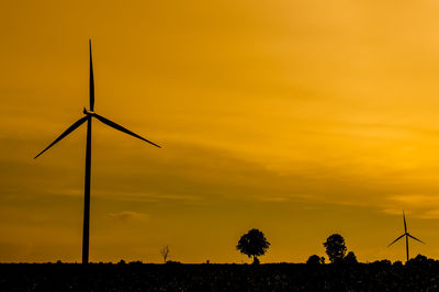 Silhouette windmill on field against romantic sky at sunset