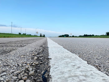 Surface level of road against clear blue sky