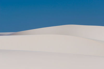 Low angle view of desert against clear blue sky