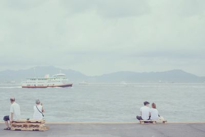 Young and senior couples overlooking boat sailing on river