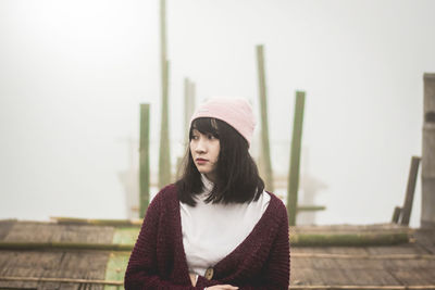 Portrait of young woman looking away against sky