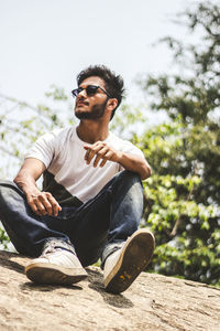 Young man wearing sunglasses sitting outdoors