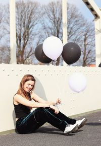 Portrait of young woman sitting with balloons