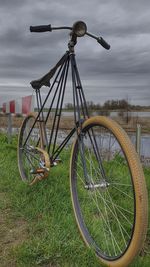 Bicycle parked on field against sky