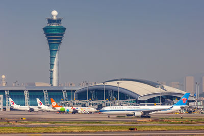 Airplane on airport runway against sky in city