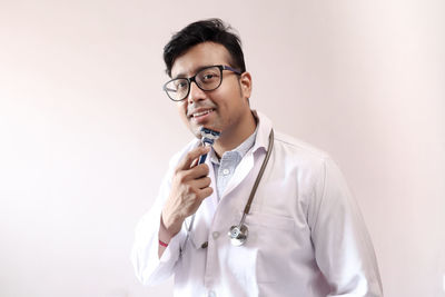 Portrait of young man standing against white background