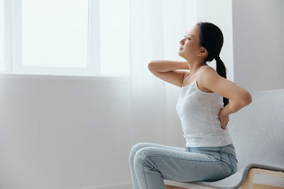 Side view of young woman exercising at home