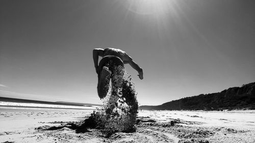 Person on beach against sky during sunny day