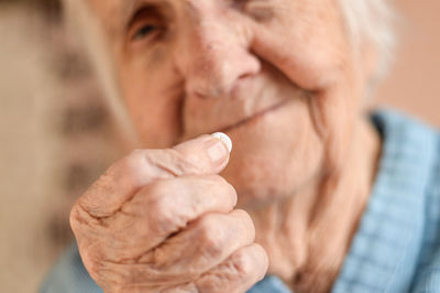 Close-up of an elderly 90-year-old gray-haired woman who is preparing to take the medicine. 
