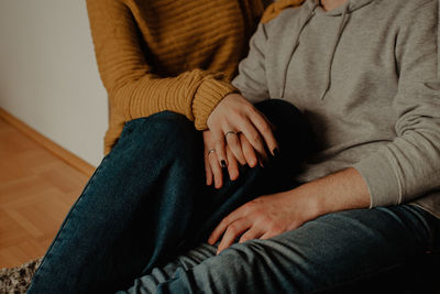 Midsection of couple sitting at home