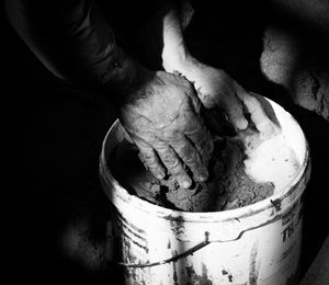 Cropped image of man mixing sand and water in bucket