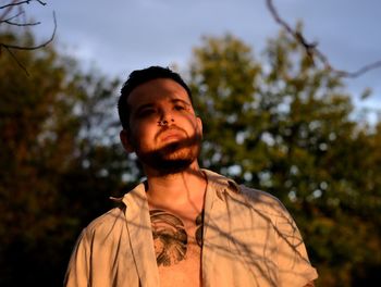 Portrait of young man standing against trees