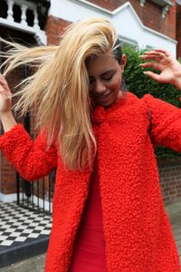 Happy young woman in red sweater tossing air on street