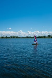 Sailboat in sea against blue sky