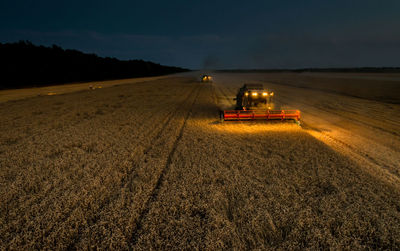 High angle view of combine harvester on field at night