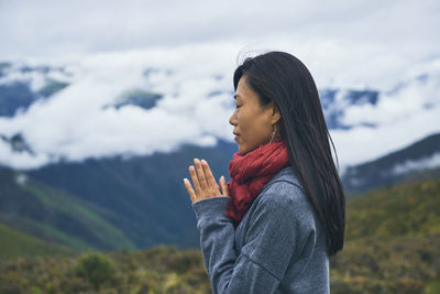 Side view of young woman standing against sky