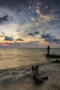 Man standing on beach against sky during sunset