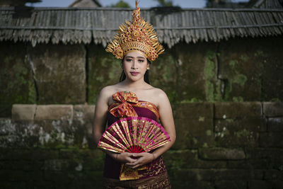 Portrait of young woman standing against building