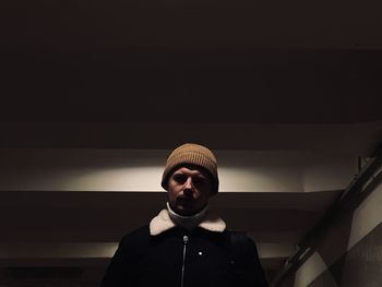 Portrait of young man standing against wall