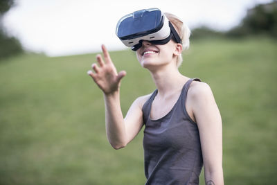 Smiling young woman using virtual reality glasses outdoors