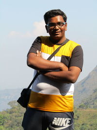 Young man standing by eyeglasses against sky