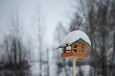 Close-up of birdhouse on tree against building during winter