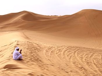 Man sitting on sand dune in desert