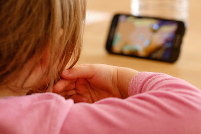 Close-up of girl using mobile phone at home