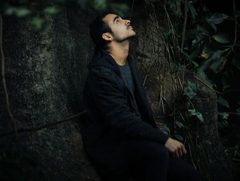 Side view of thoughtful young man looking away in forest