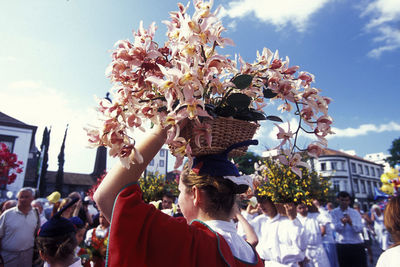 Woman carrying flowers in basket over head during traditional festival