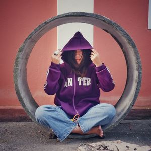 Portrait of young woman standing against wall